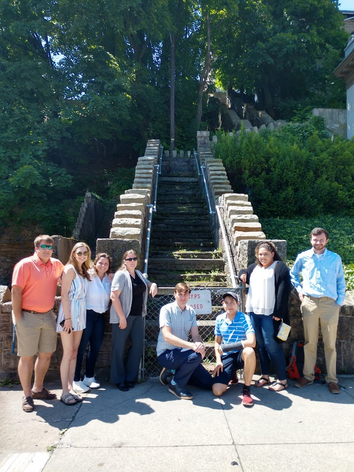 Group of students and instructor stand in front of long flight of concrete steps.